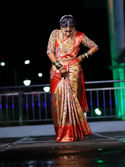 A candid moment captured at night. Even in low light, the rich texture of her silk saree and the sparkle of the embroidery on her blouse are visible.