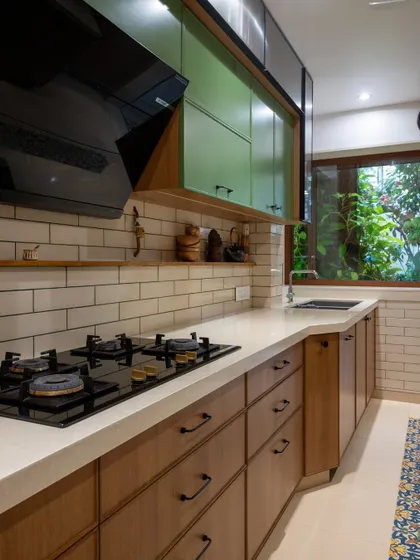 This perspective emphasizes the clean lines of the countertop and the beautiful contrast between the natural wood drawers and the white subway tile backsplash. The window brings in greenery, adding a touch of life.