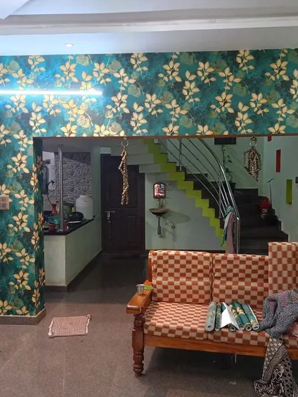 A wider view of the green and gold leaf wallpaper in a living room.