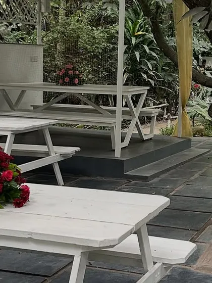 For casual outdoor seating, we provide picnic-style tables. Here, we've kept the decoration simple with a small, elegant centerpiece of red roses on each white table.