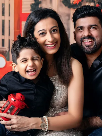A beautiful family portrait full of laughter. The red lantern adds a perfect pop of festive color to their stylish black and silver outfits.