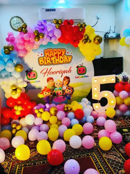 A Cocomelon party designed for a smaller space at home. The room is filled with colorful balloons on the floor and a vibrant arch over a personalized backdrop.