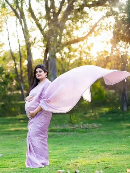 We love creating dynamic shots like this one, where the flowing pallu of the saree catches the golden hour light. This outdoor portrait feels both graceful and full of life.