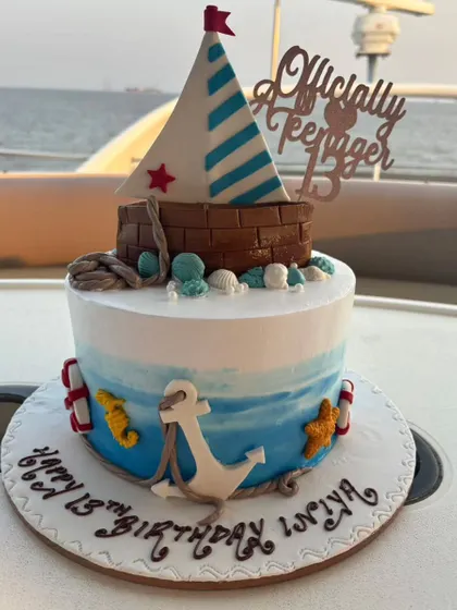 Officially a teenager! This nautical-themed cake was designed for a 13th birthday boat party. The design includes an anchor, sailboat, and ocean waves to perfectly match the celebration's setting.