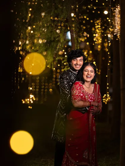 Pure happiness captured in a candid moment. The couple shares a laugh, surrounded by a magical backdrop of bokeh lights during their evening celebration.