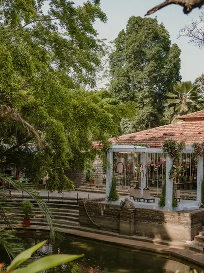 The serene beauty of The Tamarind Tree, with our custom mandap perfectly situated by the traditional temple pond, creating a tranquil space for a wedding.