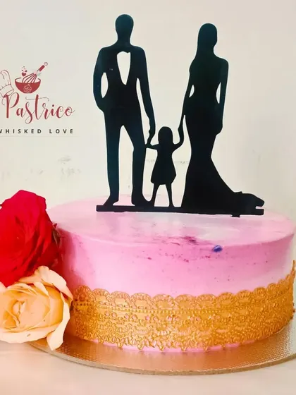 An elegant anniversary cake with a family silhouette topper, beautiful fresh roses, and a delicate gold lace border.