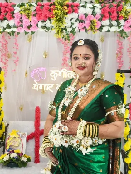 A portrait of the mom-to-be in her beautiful green saree and floral jewelry, standing before the festive baby shower decorations.