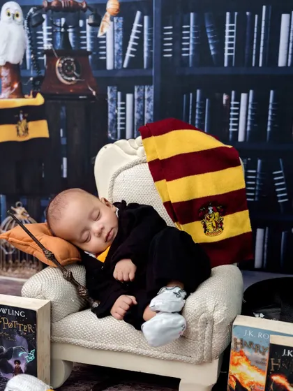 A classic shot of our little wizard sleeping in his chair, with his wand at the ready. The lighting creates a cozy, magical atmosphere.