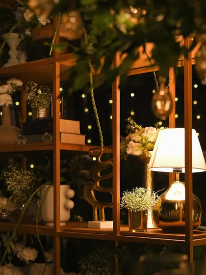 A wider view of the decorative shelves at night, with fairy lights twinkling in the background. The warm lighting creates a magical and romantic atmosphere.