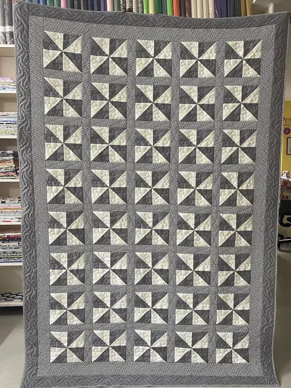 A classic "Pinwheel" quilt in a simple, elegant grey and white color scheme.