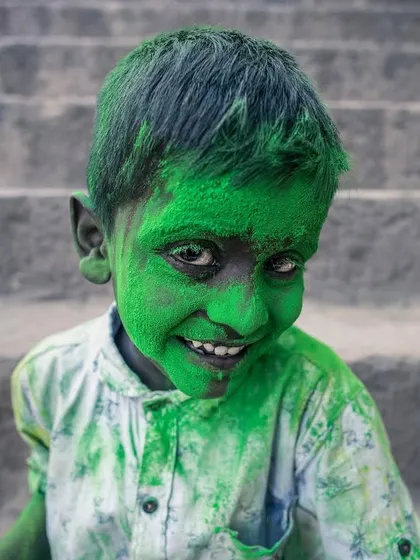 A child's face, covered in bright green powder, breaks into a joyful smile during the Holi festival in Vrindavan, the city of colors.