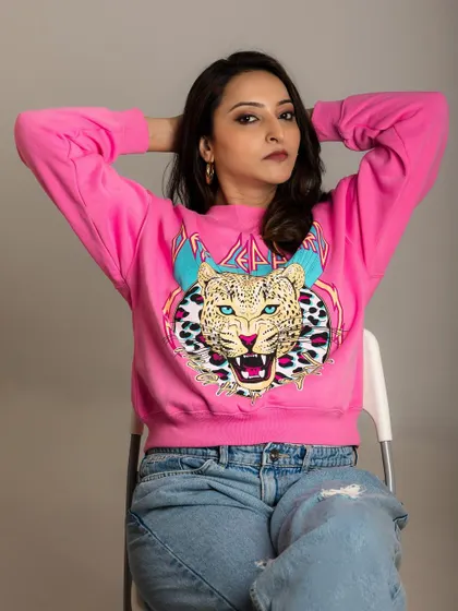 A cool and casual studio portrait. The graphic sweatshirt and relaxed pose create a look that is confident and full of personality.