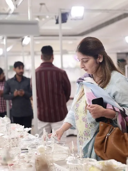 A happy shopper browsing the extensive collection of silverware at my exhibition booth. It brings me immense joy to see my creations being appreciated and chosen for special homes and occasions.
