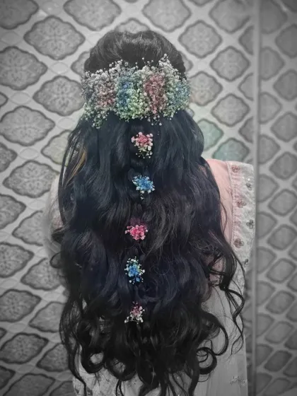 An open-hair style with lots of volume and curls. We decorated it with colorful baby's breath for a whimsical and romantic party look.