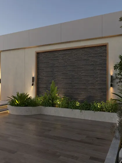 This detail of the terrace shows the built-in planters and a feature wall with wooden slats. The strategic use of up-lighting creates a sophisticated ambiance in the evening, highlighting the textures of the plants and materials.