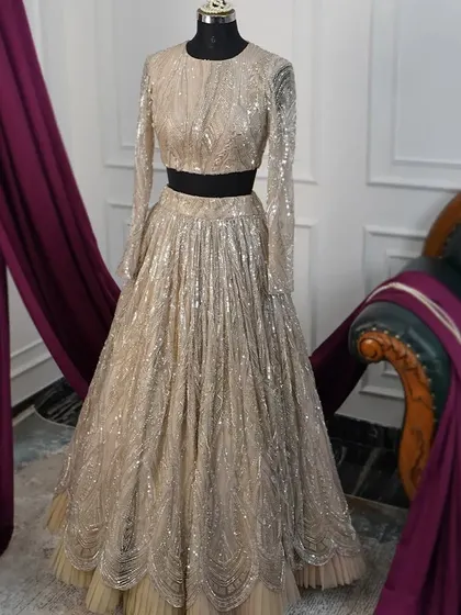 Perfect for a sangeet or reception, this gold sequin lehenga is designed to shimmer and shine. The full-sleeved crop top and flowing skirt are entirely embellished with geometric and scallop patterns, creating a dazzling and contemporary statement piece.