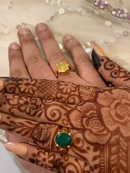 A close-up showing how the delicate floral mehendi design looks with the couple's engagement rings, marking the beginning of their journey together.