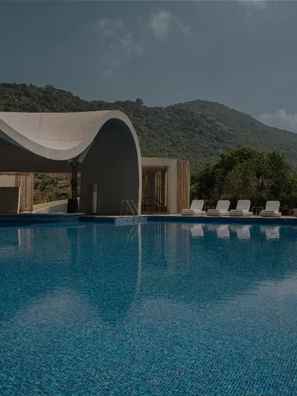 An expansive view of the infinity pool that seems to merge with the distant hills. We designed the space to prioritize the view, with the architecture acting as a frame for the natural beauty of the Karnataka landscape.