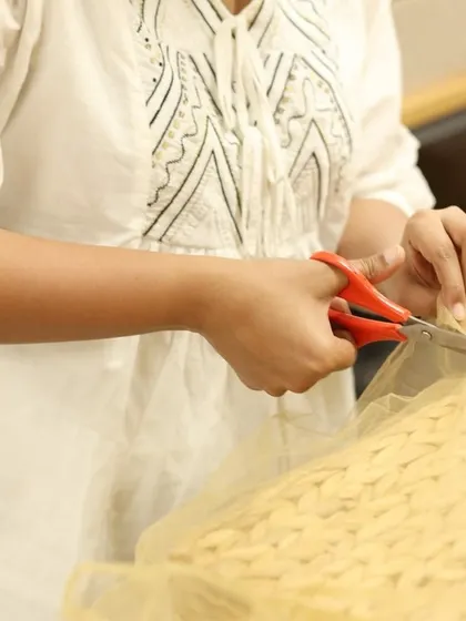A close-up of hands carefully cutting fabric for a hamper. It's this meticulous handiwork that sets our gifts apart.