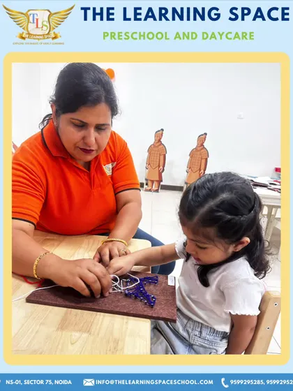 A teacher assists a young girl with her Eiffel Tower craft, ensuring she can successfully complete the project. My hands-on guidance helps build confidence and skill.