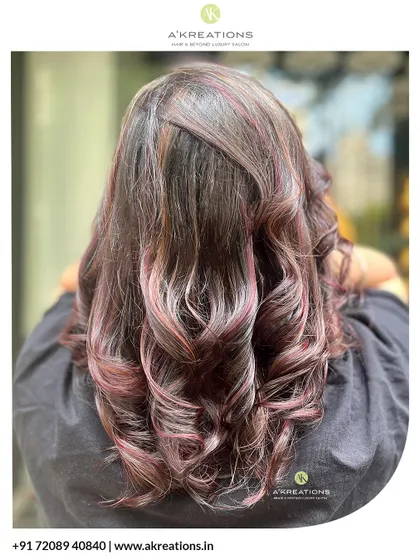 We added these beautiful pink and red highlights to give this client's hair a touch of glam and dimension, styled in soft curls.