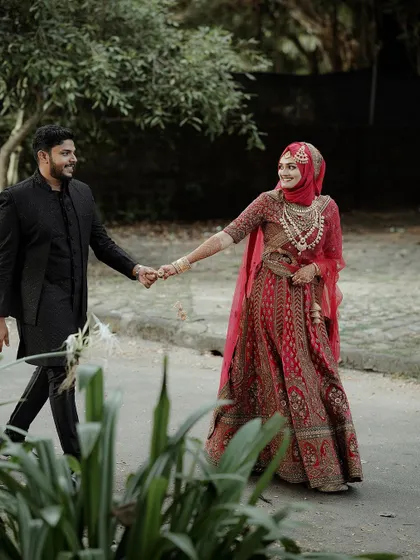 A beautiful shot of the couple walking together, the bride in her stunning red lehenga, creating a striking image of love and tradition.