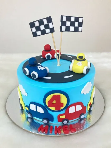 A high-speed racing theme cake for a car enthusiast. The design features a fondant racetrack, checkered flags, and colorful cars around the tier.