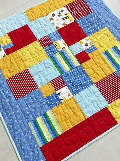 A bright and primary-colored baby quilt with a modern, abstract block design.