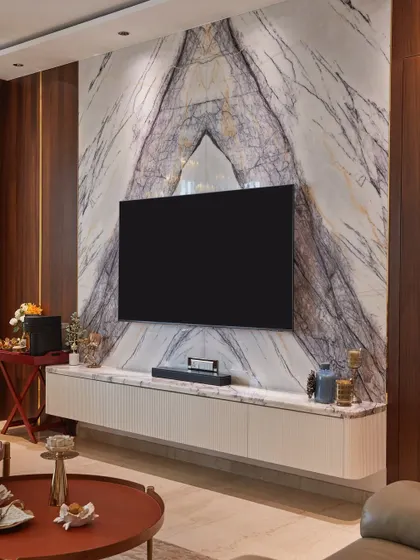 A full view of the Italian marble TV wall, which serves as a stunning focal point in this open-concept dining area. The floating console with fluted details adds a modern, clean touch.