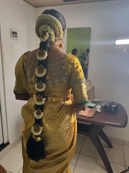 A view of Vani's traditional bridal hairstyle from the back. The long braid is adorned with jasmine flowers and a full set of jadai billai, completing her classic Muhurtham look.