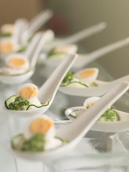 Elegant canapés featuring quail eggs, cucumber, and fresh parsley, served on individual ceramic spoons. This is a light, refreshing, and sophisticated appetizer choice for any corporate gathering.