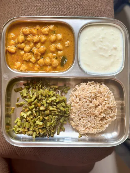 A balanced meal of brown rice, chana masala, sautéed cluster beans, and curd.