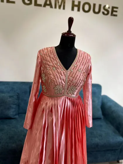 A beautiful peach-pink ombre gown with a pleated skirt and an intricately embroidered bodice.