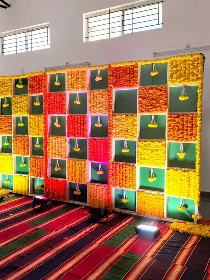 A unique backdrop for an ear piercing ceremony, made with a grid of colorful marigolds.