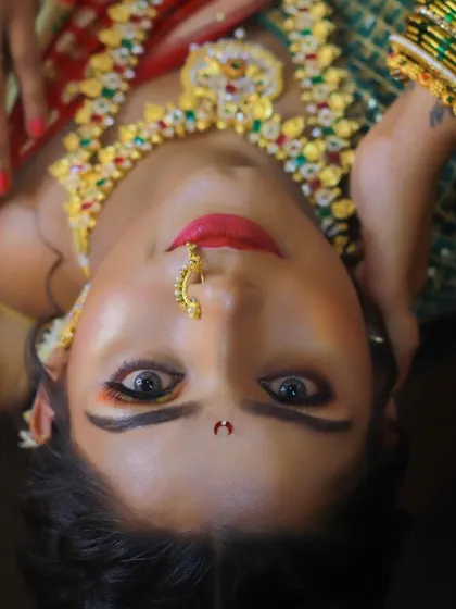 A stunning close-up of a Maharashtrian bridal look. The sunset-hued eyeshadow and bold red lip create a dramatic and beautiful effect.