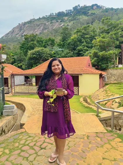 A guest poses against the backdrop of our Nandi Hills cottages and the majestic hills, a picture-perfect moment.