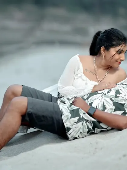 A relaxed and loving moment on the sand, capturing the easy comfort between the couple. The focus is entirely on their connection.