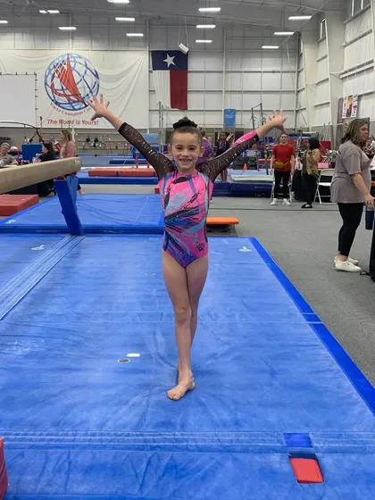 A young gymnast from our Silver team strikes her finishing pose on the mat. Every routine is a performance.