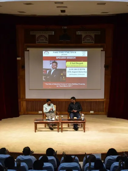 The stage setup at IIM Bangalore, with the event poster on the screen. The session was part of the Public Policy Club's speaker series.