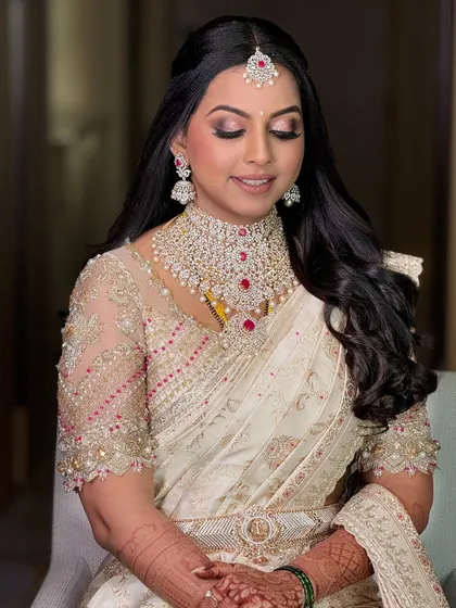 This bride is a vision in her off-white saree. The custom blouse with intricate embroidery and a modern cut makes it a perfect choice for a contemporary bride.