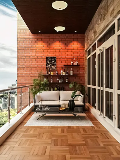This balcony is designed for entertaining, with a comfortable sofa and a wall-mounted bar shelf. The brick accent wall and parquet-style wood flooring add a touch of urban sophistication.