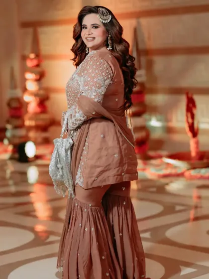 A side profile of this gorgeous sharara look. The detailed embroidery on the kurta and the flow of the pants create a flattering silhouette, perfect for a celebratory event.