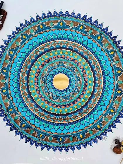 The full 'Peacock in the Desert Rain' mandala, styled with pens and natural elements, showing the tools of its creation.