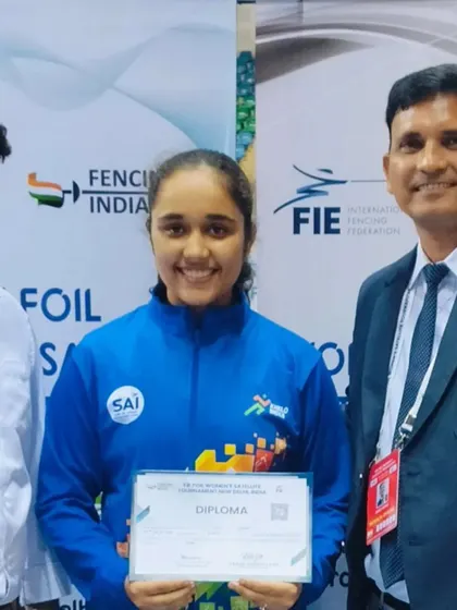Two of our coaches flank a successful fencer holding her diploma at an FIE tournament. Our coaching team provides comprehensive support to help our athletes succeed at every level.
