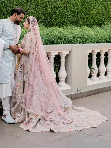 A romantic portrait of the couple, with the bride's stunning pink lehenga and long trail creating a fairytale look.