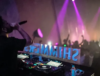 Hyping the crowd at Shimmers. The reflection of the club's name on the console adds a cool visual touch.
