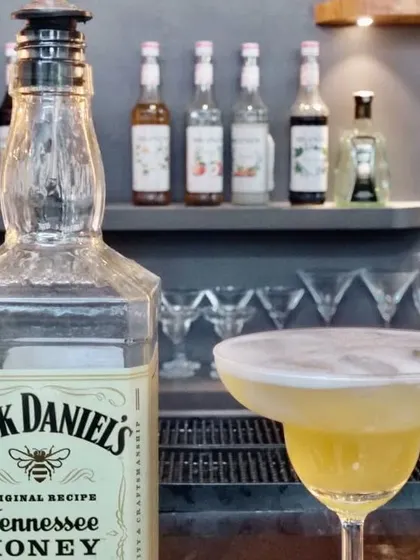 A classic whiskey cocktail made with Jack Daniel's Honey, showcasing a rich color and frothy top.
