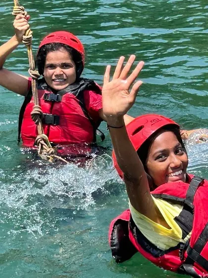 Two girls enjoy a rope swing activity in the water, another fun and challenging element of our Dandeli camp.