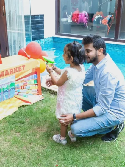 A father and daughter enjoying the water gun game together by the pool.